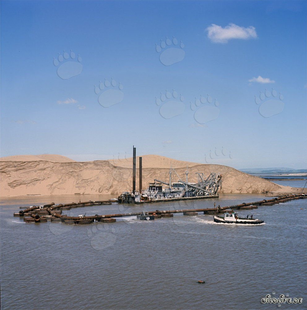 Draga de succión de cabeza de corte al atardecer frente a una duna en Richards Bay, Sudáfrica