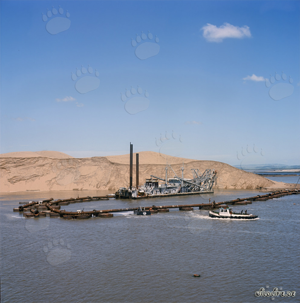 Schneidkopfspuelbagger bei Sonnenuntergang vor einer Duene in Richards Bay, Südafrika